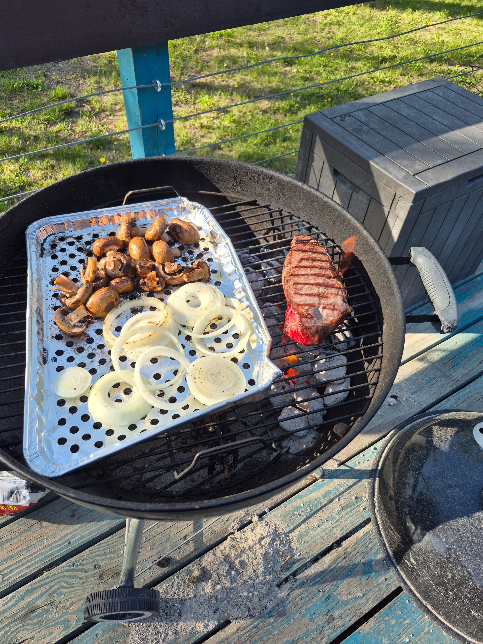 Steak, mushrooms, and onions cooking on a charcoal grill